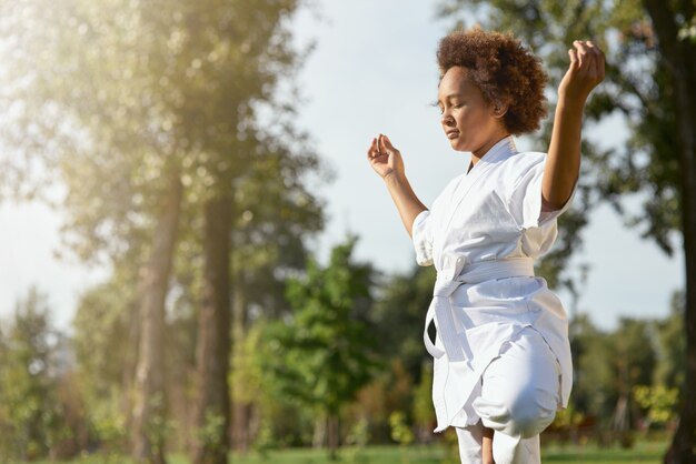 Gelassenes afroamerikanisches Mädchen im Kimono, das im Freien meditiert