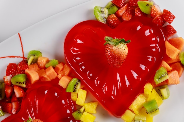 Gelatina de coração de framboesa decorada com frutas picadas na chapa branca