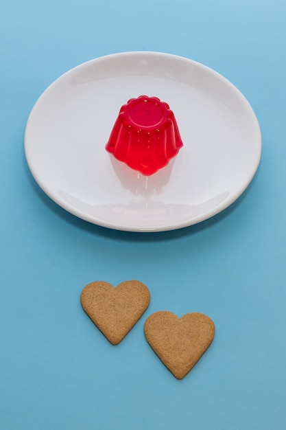 Gelatina de fresa en un plato blanco con dos galletas en forma de corazón