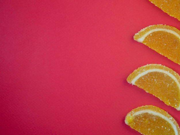 Gelatina de frutas en forma de rodajas de naranja y pomelo sobre un fondo rojoDulces sobre la mesa