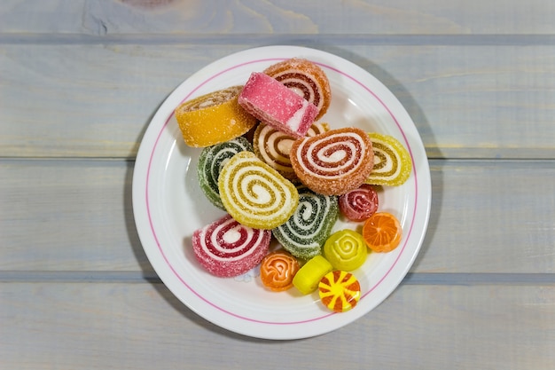 Gelatina de frutas sobre una mesa de madera, caramelo brillante sobre una superficie gris