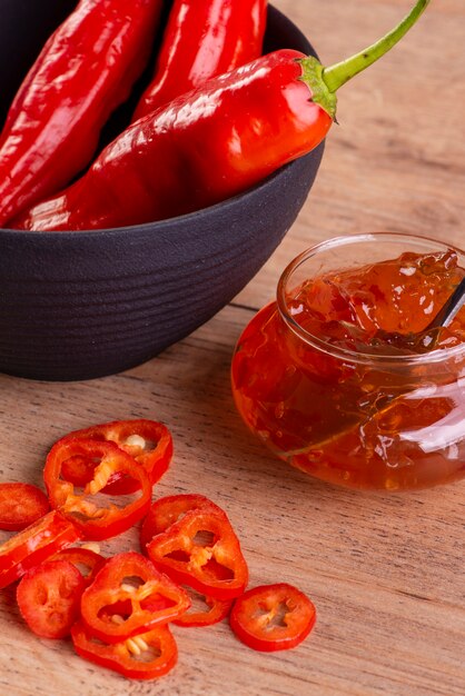 Gelatina de pimienta, pimientos enteros y en rodajas en la mesa de madera