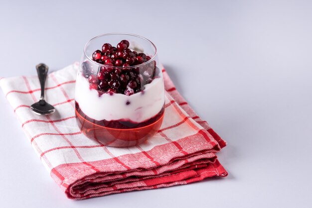 Gelatina y yogur con bayas en vidrio para Navidad sobre fondo azul Postre festivo saludable