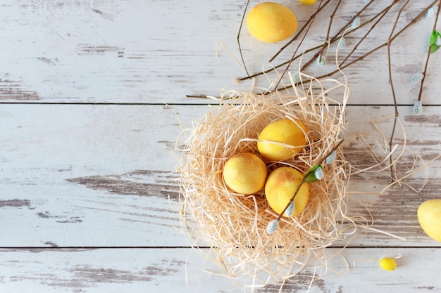 Gelb gefärbte Ostereier auf Holztisch in einem Nest Fröhliche Osterzeit