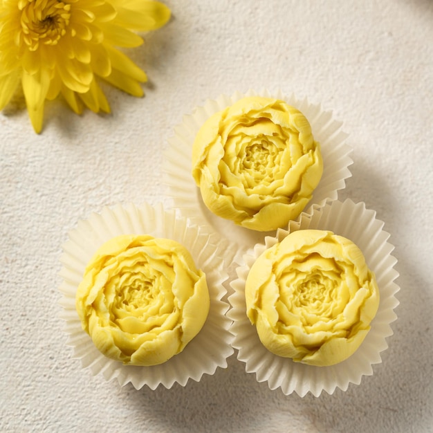 gelbe Blumen und Pralinen auf hellem Hintergrund