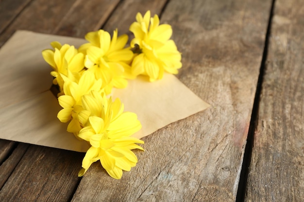 Gelbe Chrysantheme im Umschlag auf Holzuntergrund