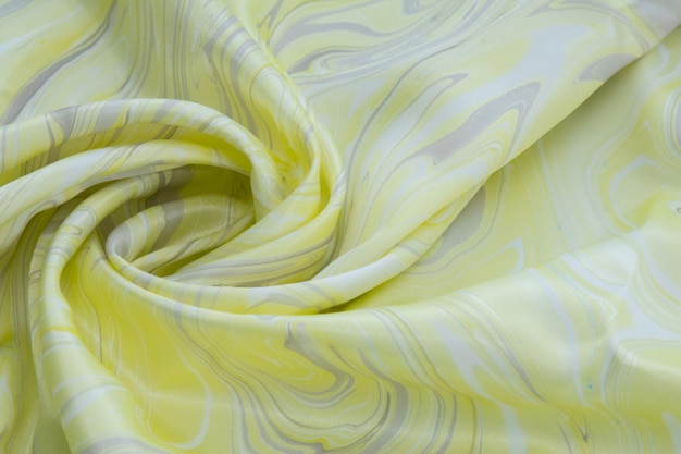 Foto gelbe draufsicht auf grundfarbenseide, stoff mit gelber marmormusterseide, wellig, spirale, falte, wirbel, hintergrund, stoffhintergrund, kopienraum für text
