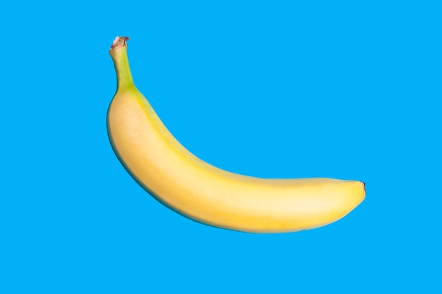 Gelbe frische Banane auf klarem blauem Hintergrund. Minimaler Stil. Ansicht von oben