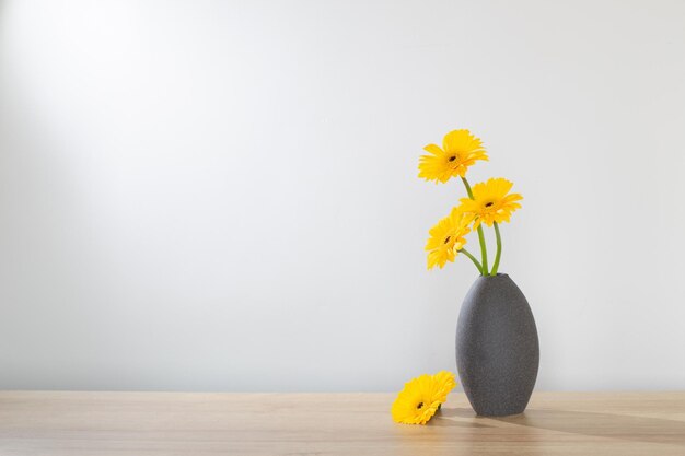 gelbe Gerbera in Vase auf Holzregal