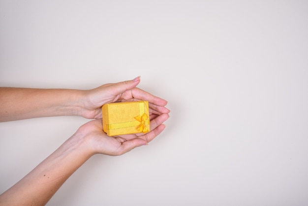 Gelbe Geschenkbox mit Schleifenband in Frauenhänden, Geburtstag