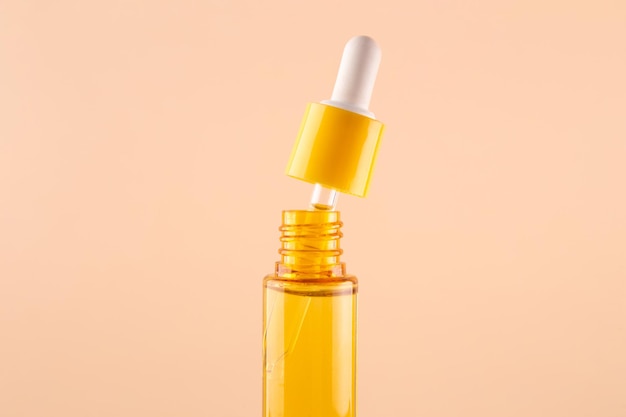Gelbe Glasflasche mit Pipette mit ätherischem Öl auf beigem Hintergrund Draufsicht Aromatische Kosmetik