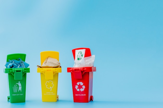 Gelbe, grüne und rote Papierkörbe mit Recycling-Symbol auf blauem Hintergrund. Stadt sauber halten, Lässt das Recycling-Symbol. Naturschutzkonzept.