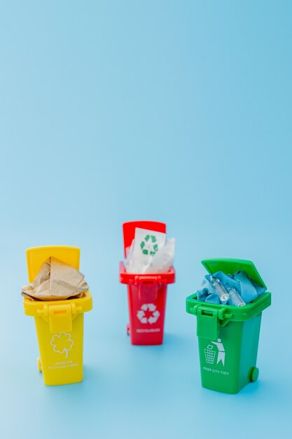 Gelbe, grüne und rote Papierkörbe mit Recycling-Symbol