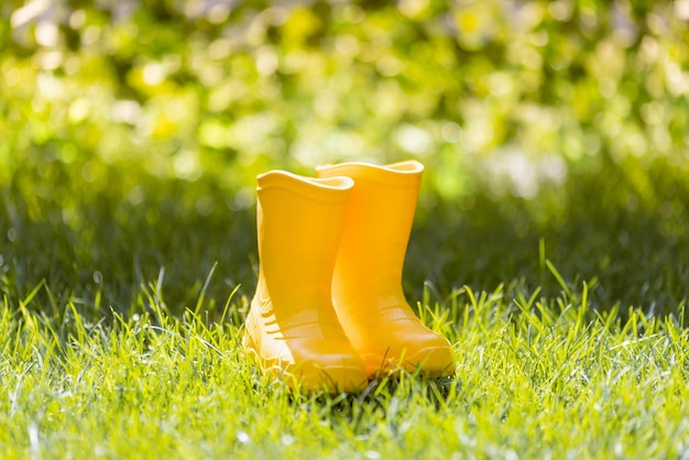 Gelbe Gummistiefel vor verschwommenem Blätterhintergrund