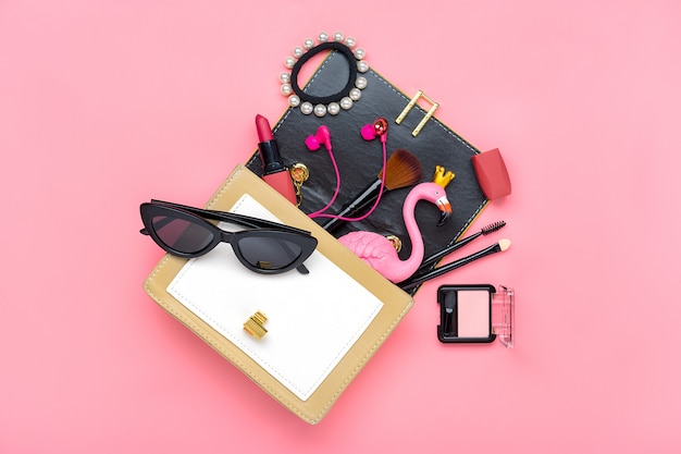 Foto gelbe handtasche mit frauenaccessoires auf rosa tisch