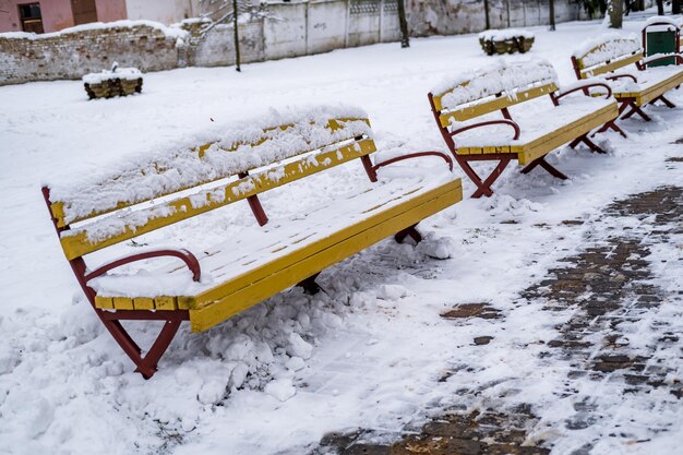 Gelbe Holzparkbänke mit Schnee bedeckt