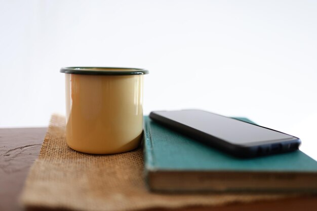 Gelbe Kaffeetassen, Telefone und Bücher auf dem Holztisch im Haus.