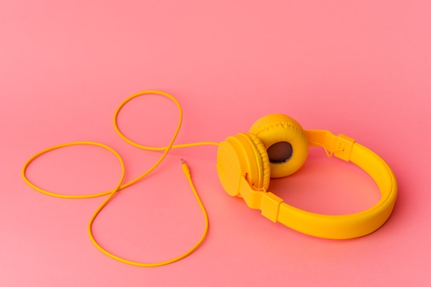 Gelbe Kopfhörer auf rosa Hintergrund isoliert