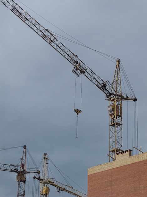 Gelbe Kräne auf dem Hintergrund von Gebäuden im Bau