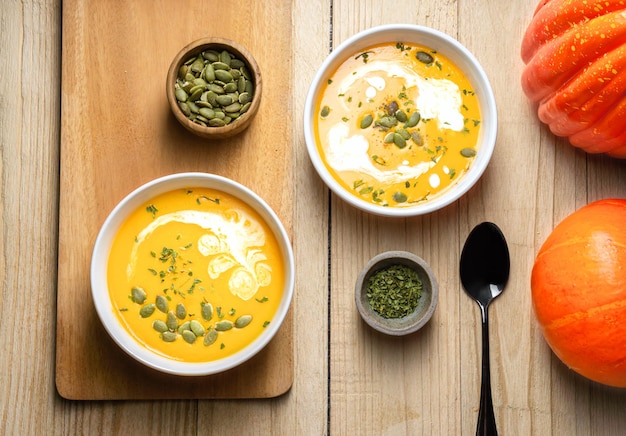 Gelbe Kürbissuppe mit cremefarbenem Kürbiskern und Petersilie auf Holzhintergrund Kopierbereich Ansicht von oben