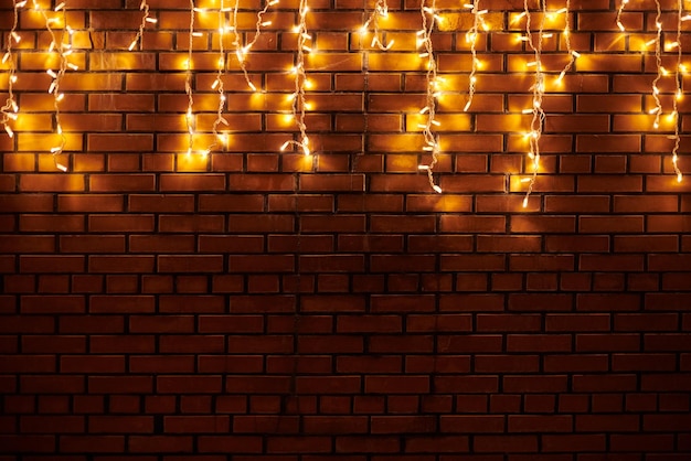 Gelbe Lichtgirlanden hängen von der roten Ziegelwand am Abend schöne Weihnachtshausdekoration