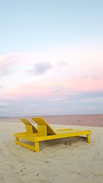 Gelbe Loungestühle am Meer am Sonnenuntergang gegen den Himmel