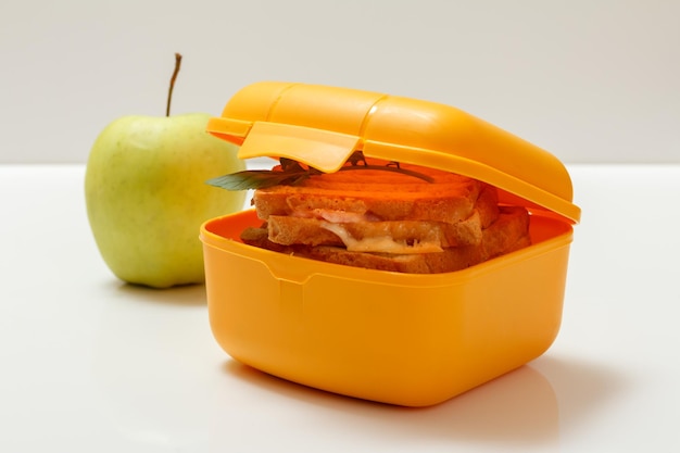 Gelbe Lunchbox mit gerösteten Scheiben Brotkäse und grüner Petersilie