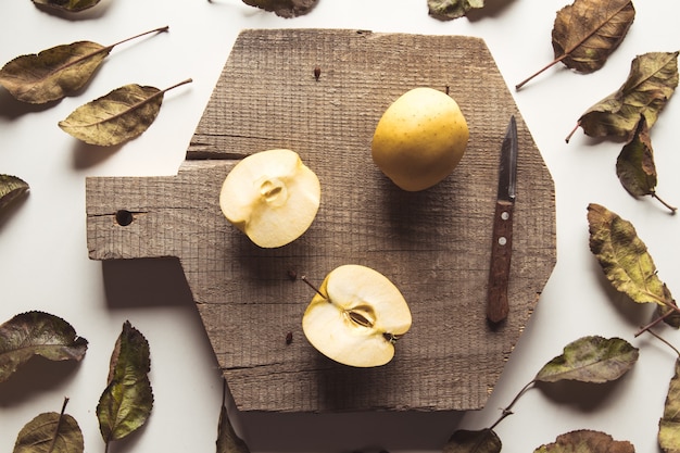 Gelbe Äpfel auf einem geschnittenen Brett im Vintage-Stil. Blätter, Lebensmittel, gesunde Lebensmittel, vegan, landwirtschaftliche Produkte.