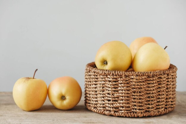 Gelbe Äpfel in einem runden Weidenkorb auf einem Holztisch Leeren Platz für Text kopieren