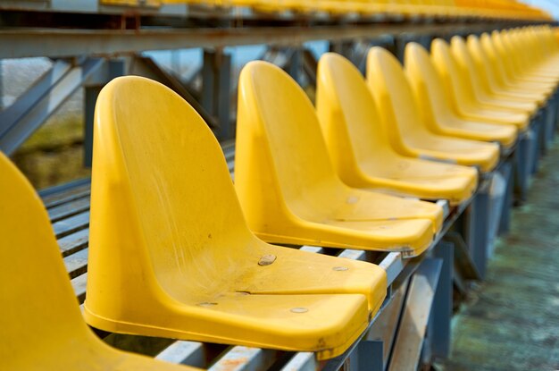 Gelbe Plastiksitze auf dem Podium eines kleinen Sportplatzes.