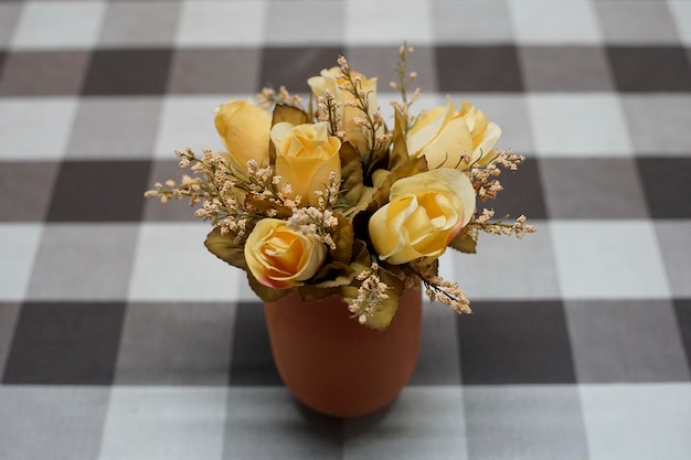 Gelbe Rosen in einer Vase auf einem Tisch mit karierter Tischdecke
