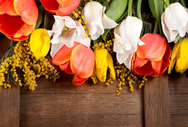 Gelbe rote und weiße Frühlingsblumen auf hölzernen Hintergrundtulpen