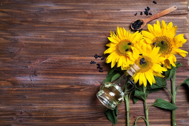 Gelbe sonnenblumen mit ölglasflasche auf hintergrund des alten zauns.