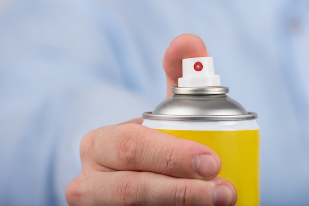 Gelbe Sprühflasche in der Hand. Nahansicht. Vorderansicht.