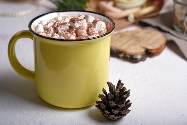 Gelbe Tasse mit Kakao verziert mit Marshmallows Nahaufnahme, Marshmallows auf dem Hintergrund