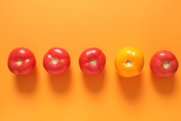 Gelbe Tomate unter roten auf Orange