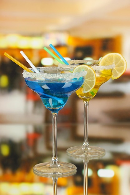 Gelbe und blaue Cocktails in Gläsern auf Raumhintergrund