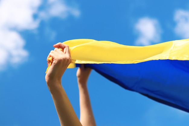 Gelbe und blaue Flagge der Ukraine in den Händen der Frau. Flatternde blaue und gelbe Flagge der Ukraine