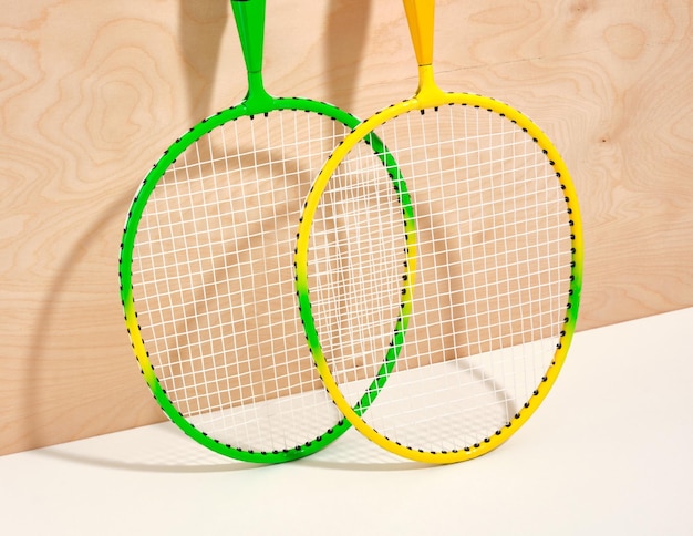 Gelbe und grüne Sport-Badmintonschläger auf einem hölzernen Hintergrund. Set aus verschiedenen Sportartikeln
