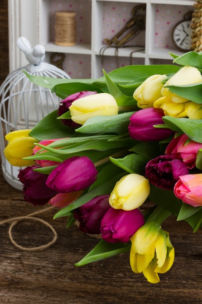 Gelbe und lila frische Tulpen schließen oben auf Holztisch