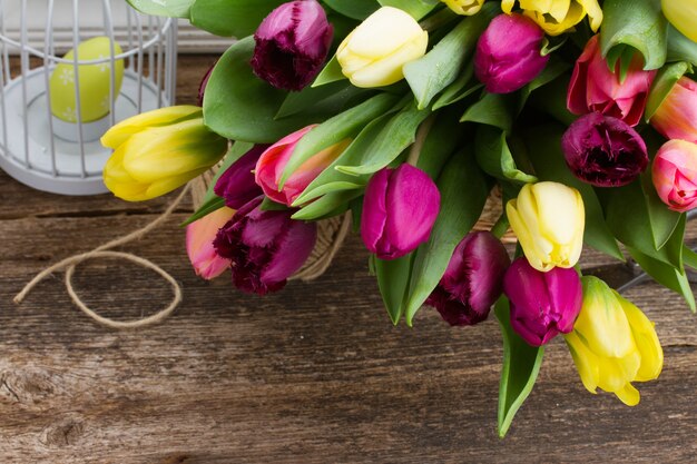 Gelbe und lila frische Tulpenblumen auf Holztisch