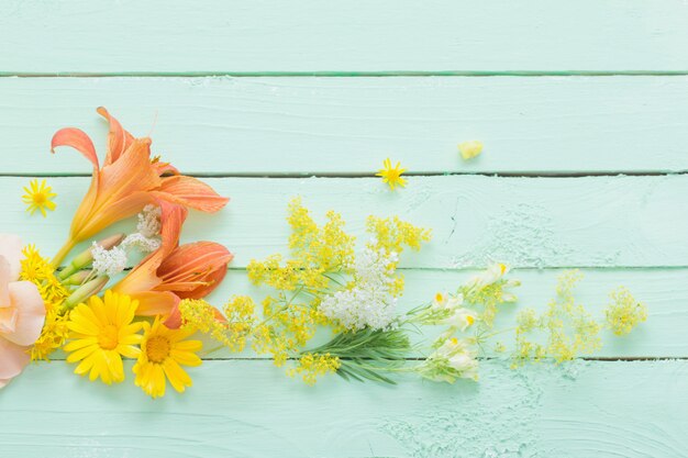 Gelbe und orange Blumen auf grünem Holz