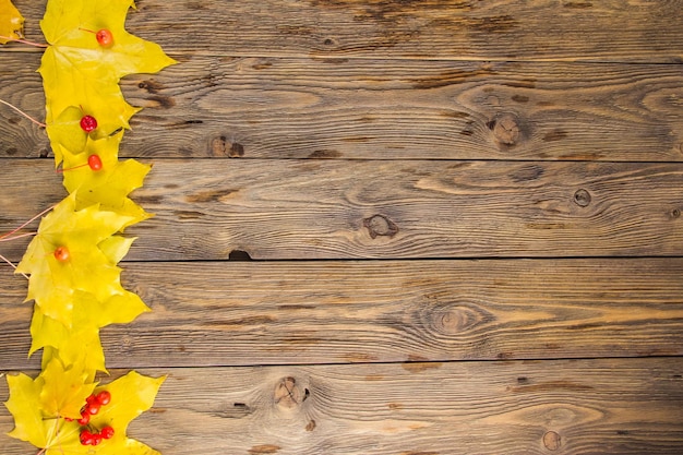 Gelbe und orange gefallene Ahornblätter auf dunkelbraunem Holztisch