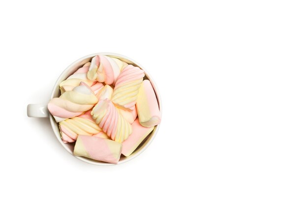 Gelbe und rosa Marshmallows in einer Tasse und auf einem weißen Hintergrund