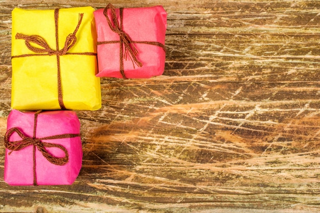 Foto gelbe und rosa weihnachtsgeschenke liegen auf einer verkratzten holzoberfläche.