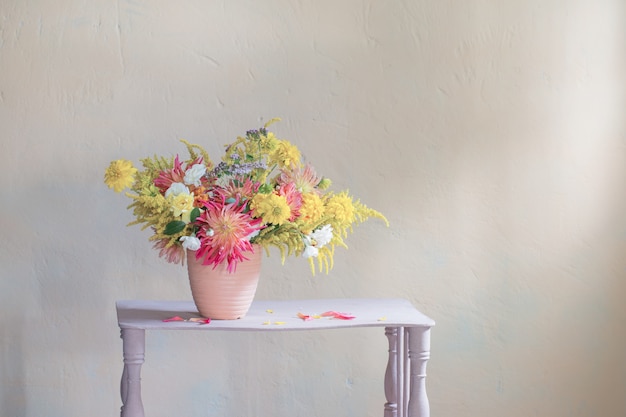 Gelbe und rote Blumen in der Vase auf Vintage-Regal