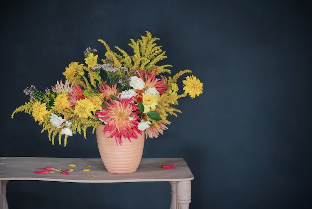 Gelbe und rote blumen in der vase auf vintage-regal