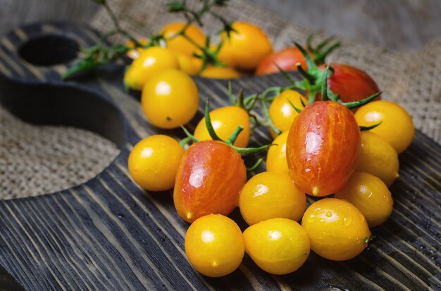 Gelbe und rote Kirschtomaten auf hölzernem Schneidebrett.