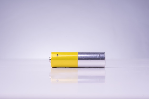 Gelbe und silberne alkalische AA-Batterie auf weißem Hintergrund mit Reflexion