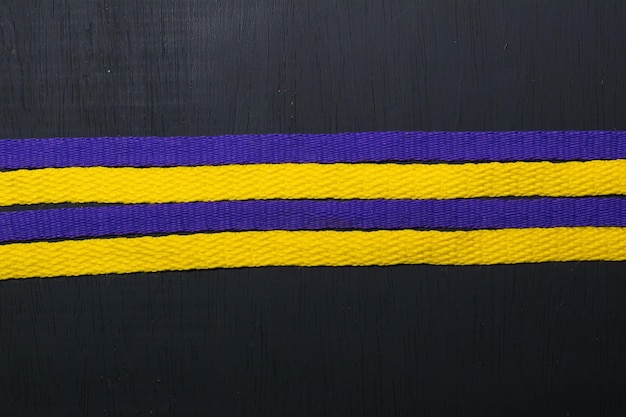 Gelbe und violette Schnürsenkel, Lakers-Flagge auf schwarzem Holzhintergrund, die Platz für Text lässt